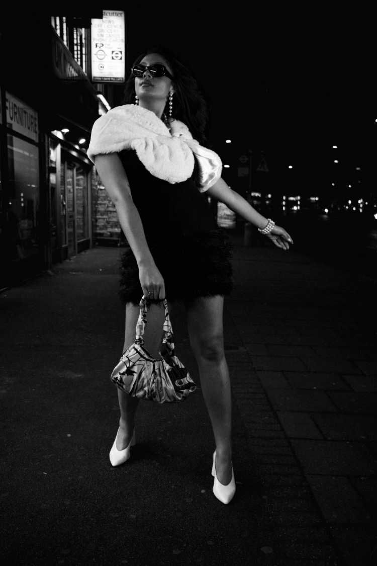 Woman in a black feather-trim dress opening a purple bag at a fast-food counter