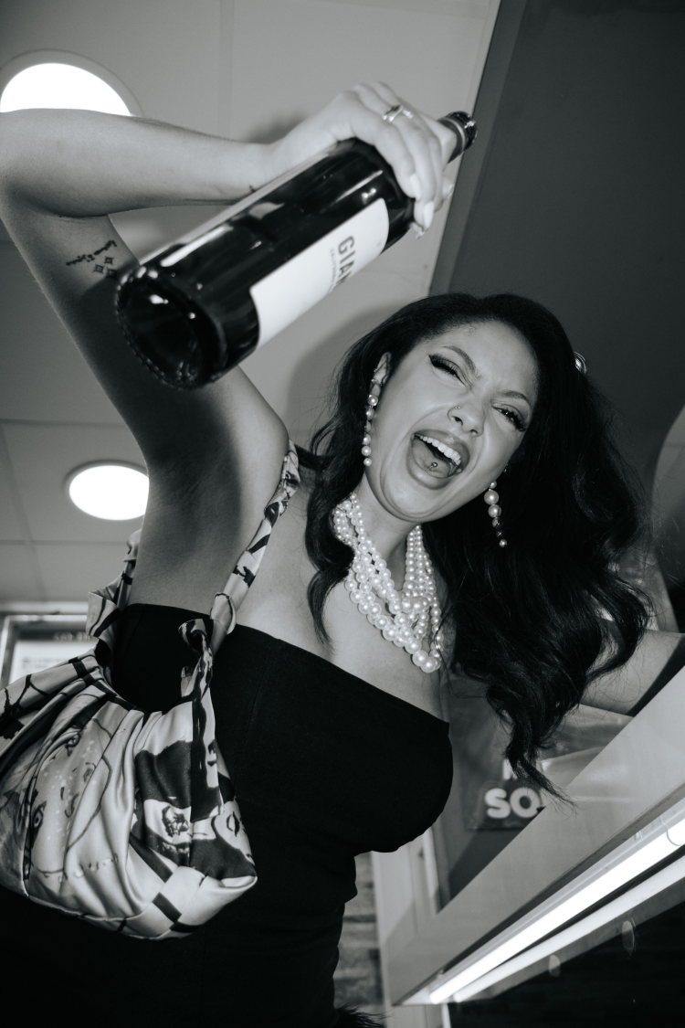 Close-up of a woman in sunglasses and a white fur wrap biting into a fried chicken tender
