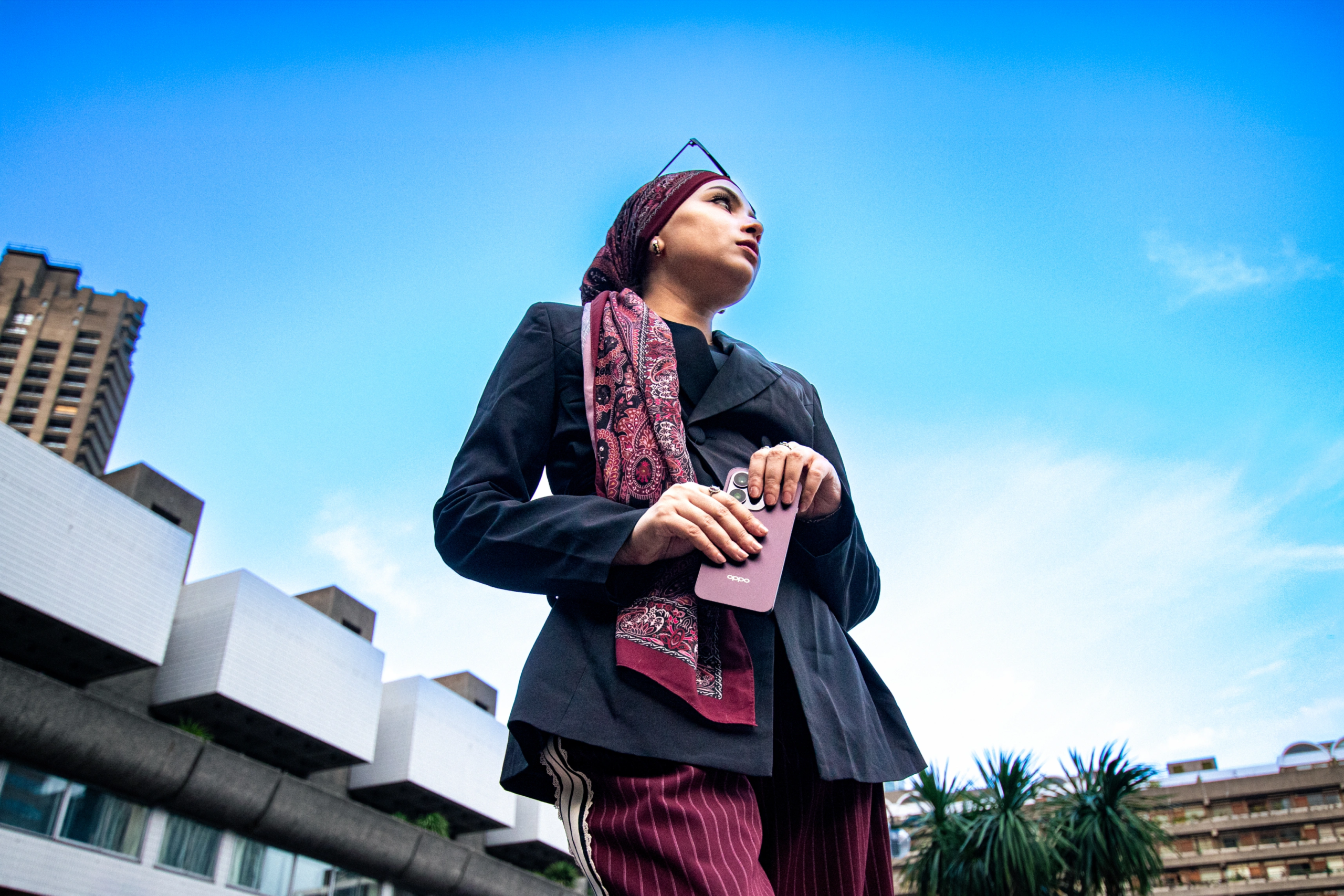 Low-angle photograph of a woman on a phone call in front of the Barbican Centre