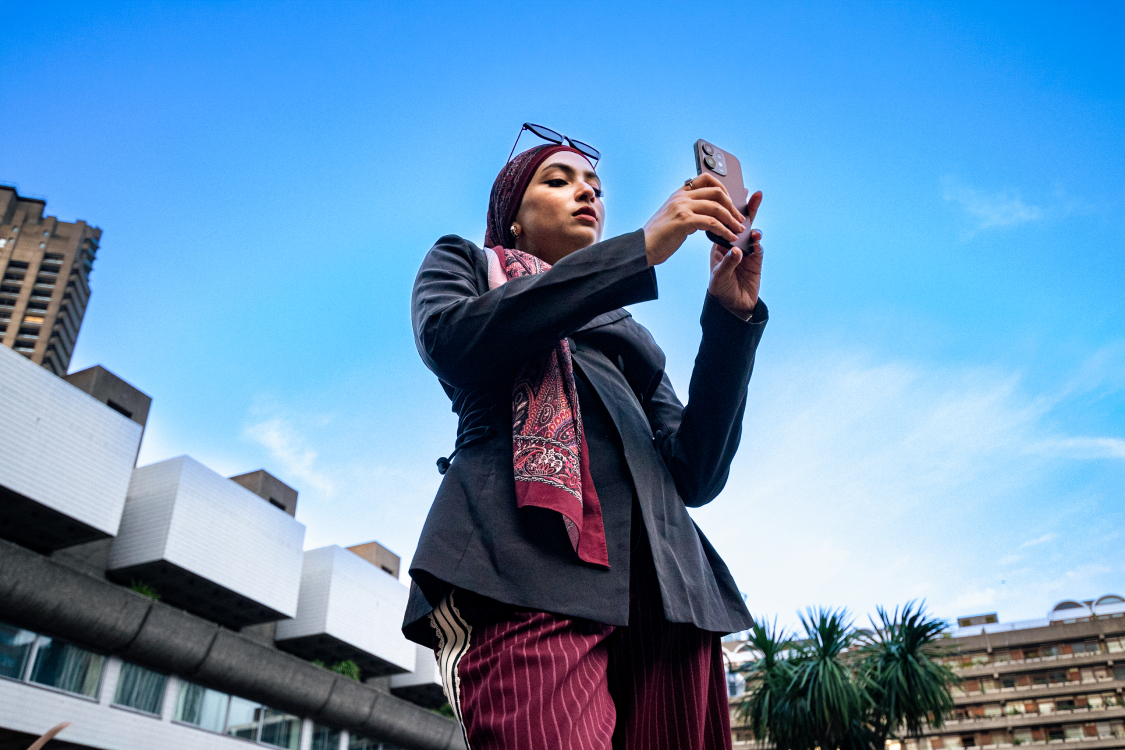 Low-angle photograph of a woman on a phone call in front of the Barbican Centre, alternate angle