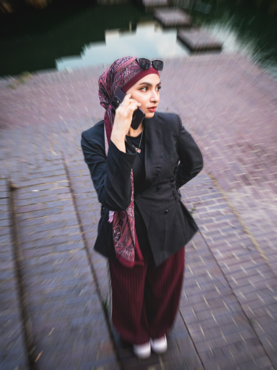 Overhead, motion-blurred photograph of a woman on a phone call beside water