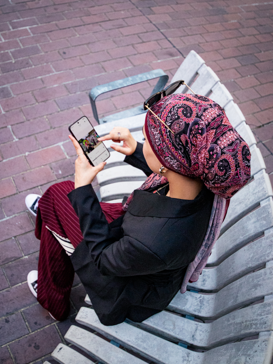 Woman photographing herself on her phone with Barbican buildings behind her